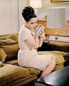 a woman sitting on top of a couch next to a table with a book in her hand