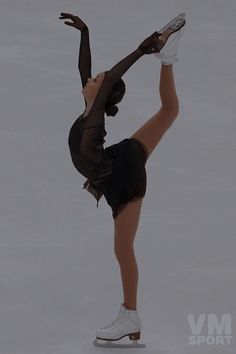 a female figure skating on the ice in a short skirt and white sneakers with her arms extended