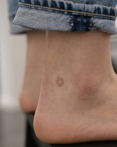 a person with a small sun tattoo on their foot and the bottom part of her leg