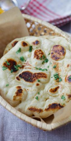 three flat breads in a basket on a table with other food items around it