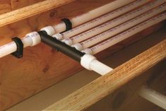 two white pipes are attached to the side of a wooden structure with black and white piping