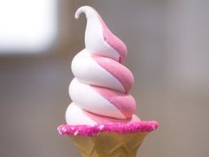 a pink and white ice cream cone with sprinkles on it's tip