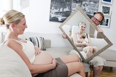 a pregnant woman sitting on a couch looking at herself in the mirror with her reflection