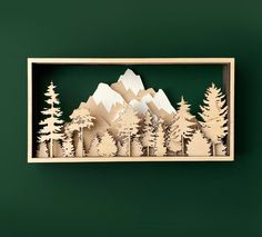 a wooden cutout of mountains and trees on a green background with text that reads, the