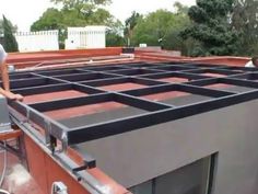 two men are working on the roof of a house that is being built with red bricks