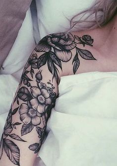 a woman laying in bed with a tattoo on her arm