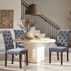 a dining room table with chairs and a vase on top of it in front of stairs