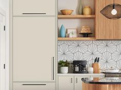 a kitchen with white cabinets and black counter tops in front of a wooden shelf filled with utensils