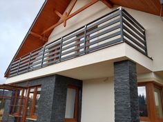 a modern house with wood and stone accents on the outside, including balcony railings