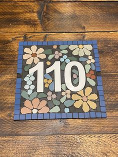 the number 101 is made out of colorful flowers on a wooden floor with blue and green tiles