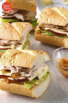 several sandwiches with meat, cheese and lettuce sitting on top of a table