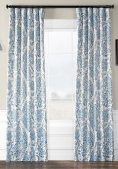 a blue and white curtain hanging in front of a window with an ornate pattern on it