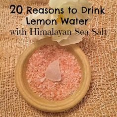 a bowl filled with pink sea salt next to a flower on top of a table