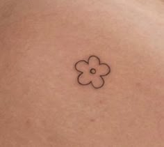 a woman's back with a small flower tattoo on it