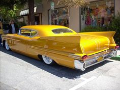 an old yellow car parked in front of a store