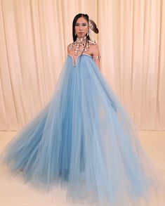 a woman in a blue dress standing next to a curtain