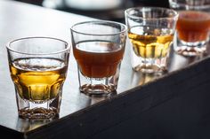 three glasses filled with liquid sitting on top of a table