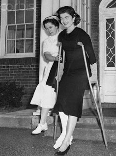 black and white photograph of two women standing on steps with crutches in their hands