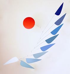 a red ball flying through the air next to some blue and white shapes on a wall