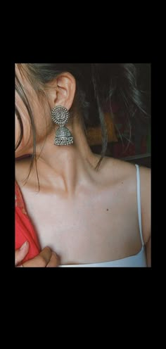 a woman is holding her ear up to the side with an earring on it