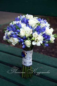 a bouquet of white and blue flowers in a vase sitting on a green park bench