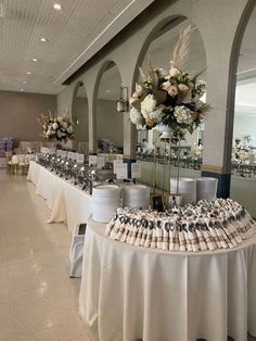 a banquet hall with tables and chairs covered in white tablecloths, decorated with flowers