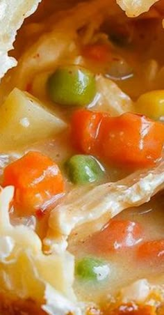 a close up view of a bowl of chicken pot pie with carrots and peas