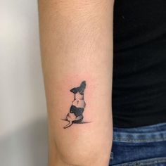 a small black and white dog tattoo on the left inner arm, with one paw in the air