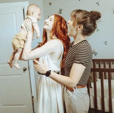 two women are holding a baby in their arms