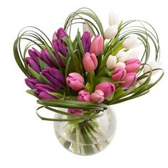 a vase filled with lots of pink and white tulips on top of a table