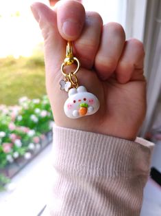 a hand holding a hello kitty keychain with an orange and white cat on it