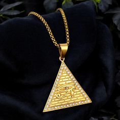 Make a statement with this bold gold pyramid necklace featuring the Eye of Horus, a powerful symbol of protection and healing. Iced out with sparkling cubic zirconia stones, this pendant exudes confidence and style. Size: Chain length - 50cm Key Features: - Gold-Plated Pyramid Pendant - Iced Out CZ Stones - Symbolic & Meaningful At EyeSpyEvilEye, our family has dedicated over 4 years to designing and crafting quality products. Your support means the world to us as we continue to pursue our passi Horus Necklace, Egyptian Pendant, Eye Of Horus Necklace, Pyramid Necklace, Pyramid Eye, Eye Of Horus, Jewelry Statement, Hip Hop Jewelry, Cz Stone