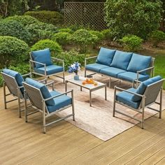 a patio with blue cushions and furniture on the wooden decking area in front of some bushes