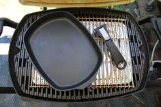 a grill with an iron skillet and spatula on it next to another cooking utensil