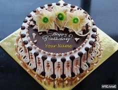 a birthday cake decorated with flowers and chocolates on a gold plated serving platter