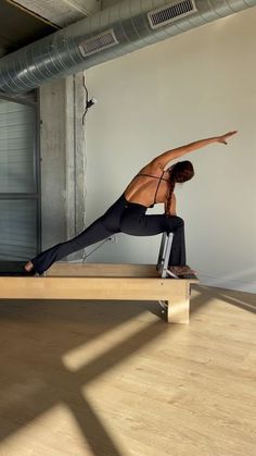 a man is doing yoga on a wooden bench in the middle of an empty room