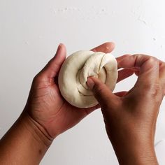 a person holding a doughnut in their left hand, with the other hand reaching for it