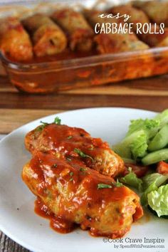 a white plate topped with meat covered in marinara sauce and veggies next to a casserole