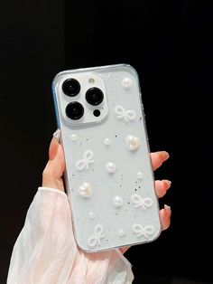 a woman holding up her phone case with pearls on it