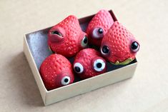 some red strawberries with googly eyes in a box