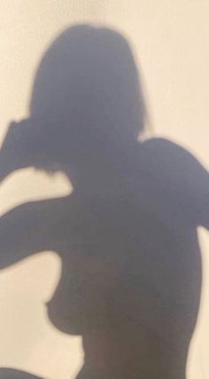 the shadow of a person holding a skateboard in front of a wall with a white background