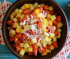 a brown bowl filled with fruit and cheese on top of a blue table cloth next to an orange napkin