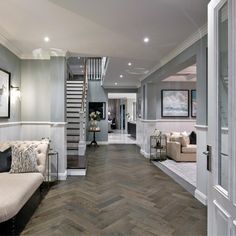 a living room filled with furniture next to a stair case and wooden floored floors