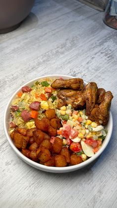 a white bowl filled with fried food on top of a wooden table next to a potted plant