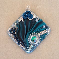 a blue and green beaded brooch sitting on top of a white countertop