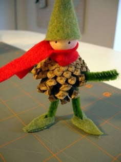 a pine cone bird with a red scarf on it's head is standing next to a pile of pine cones