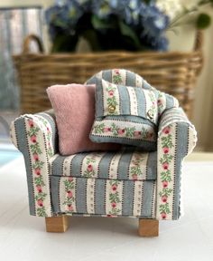 a miniature chair with a pink pillow on it