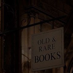 an old and rare book store sign hanging from the side of a building at night