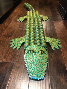 an alligator made out of paper sitting on top of a wooden floor