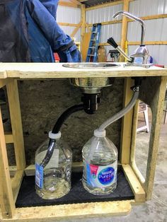 two water bottles are connected to a faucet under a workbench that is being built